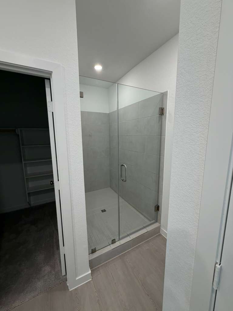 Compact frameless shower door with brushed nickel handle